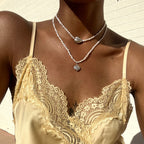 Model wearing layered freshwater pearl necklace and silver chain necklaces